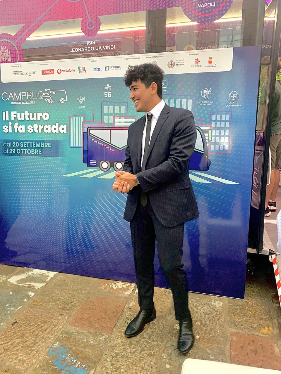 A man in a suit and tie standing in front of a sign that says it's future goes on